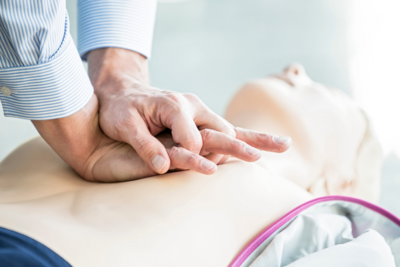 hands performing CPR on dummy manequin