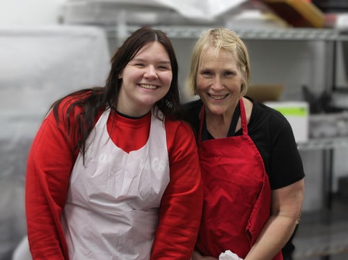 two women with aprons serving food