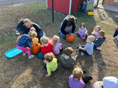 children helping carve a pumpkin